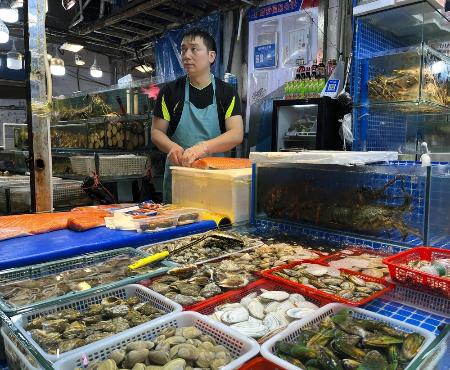 中国北京市にある海鮮市場の鮮魚店で、水産物を販売する従業員＝６月