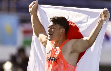 男子円盤投げで優勝し、笑顔で日の丸を掲げる湯上剛輝＝駒沢陸上競技場