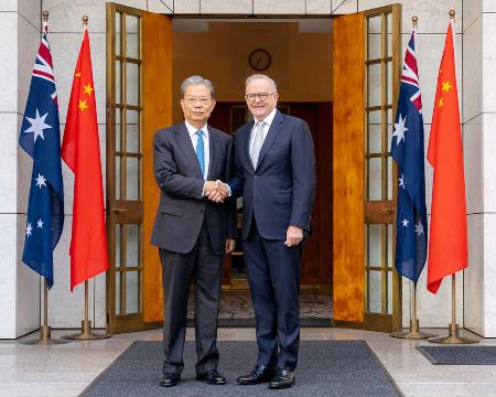 オーストラリア・キャンベラで、アルバニージー首相（右）と握手を交わす中国の趙楽際・全人代常務委員長＝２５日（首相府提供・共同）