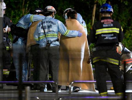 閉じ込められた観覧車から救助され、消防隊員に毛布をかけられる乗客＝２６日午前２時４２分、大阪府吹田市