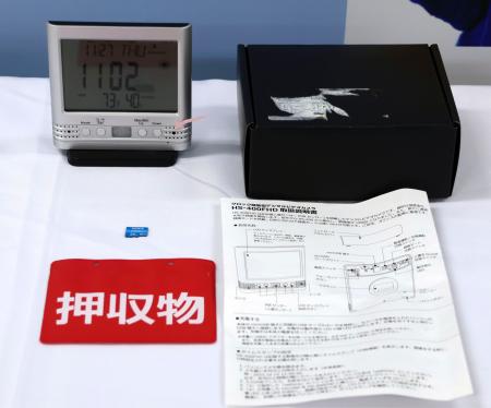 デジタル時計型の小型カメラ（左上）などの押収物＝２７日午前、愛知県警本部