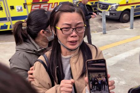 火災が起きた高層住宅で一緒に住む娘を捜す母親（右）＝２７日、香港（共同）