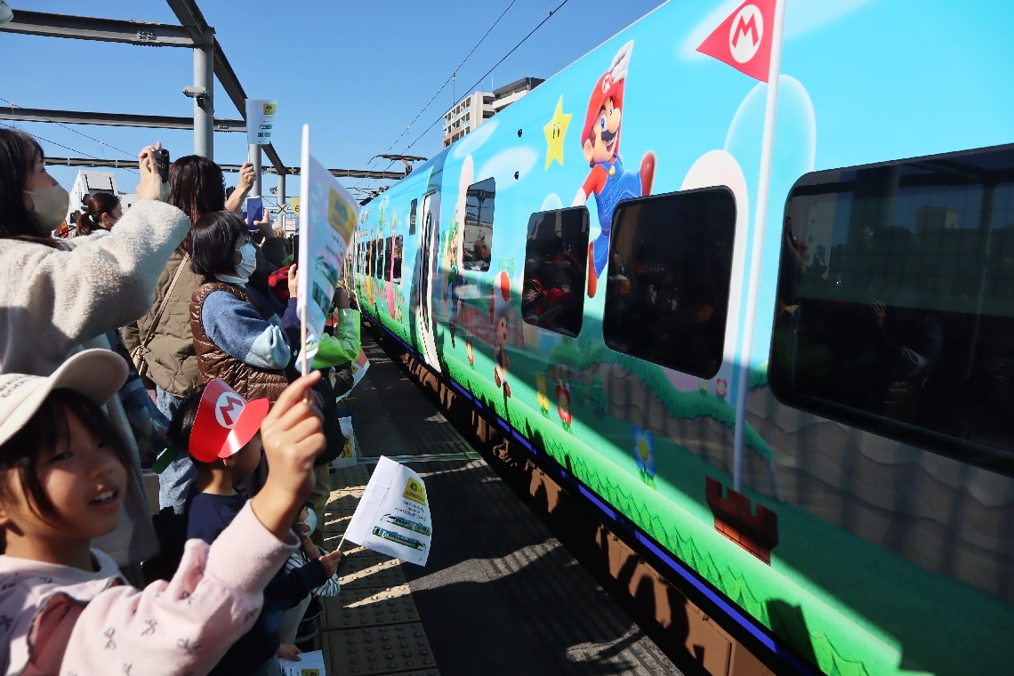 人気キャラクターをあしらったソニックを家族連れらが手旗を振って歓迎＝２９日、ＪＲ大分駅