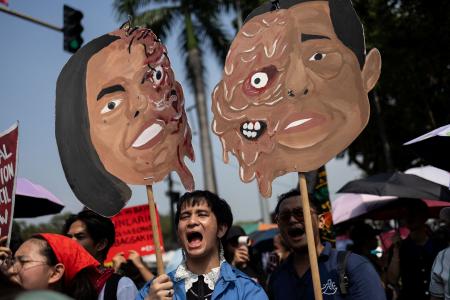 マルコス大統領とサラ・ドゥテルテ副大統領のイラストを掲げ、抗議するデモ参加者ら＝３０日、マニラ（ロイター＝共同）