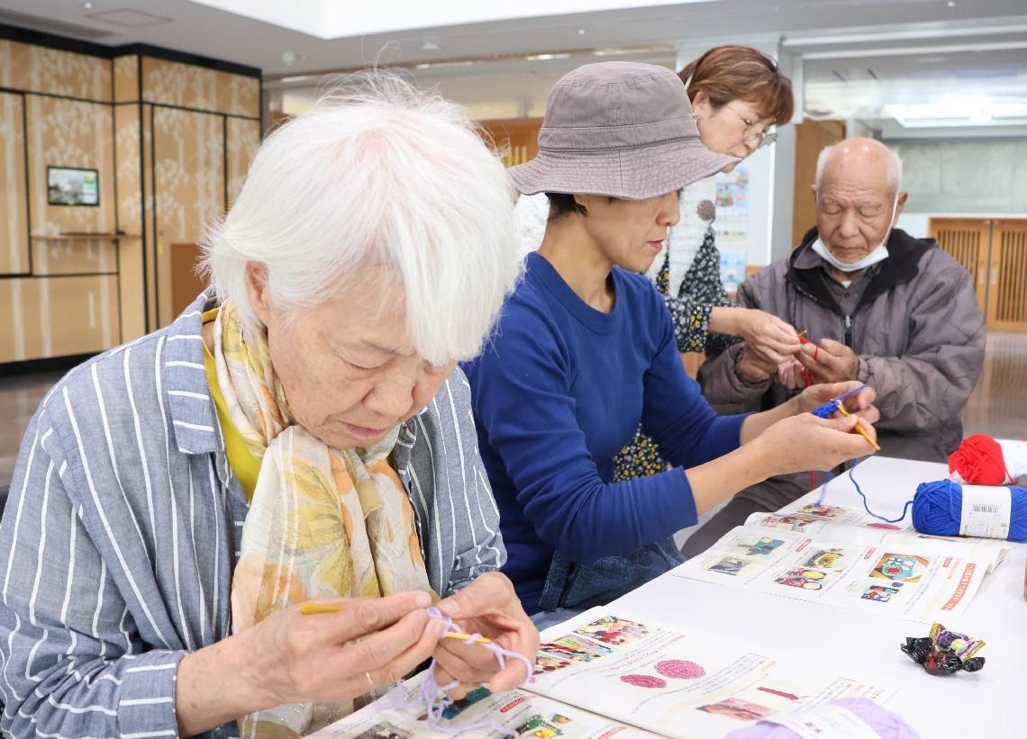認知症マフの編み方を習う参加者ら