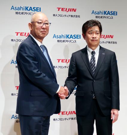 記者会見で握手する帝人フロンティアの平田恭成社長（左）と旭化成アドバンスの春見恵司社長＝２日午後、東京都内