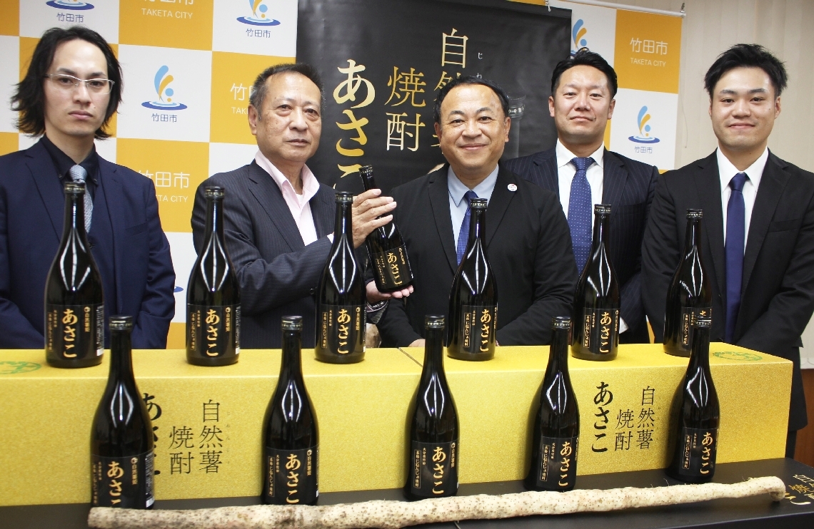 自然薯焼酎「あさこ」を土居昌弘市長（中央）披露するルックスの渡久地政宗社長（左から２人目）ら＝竹田市役所