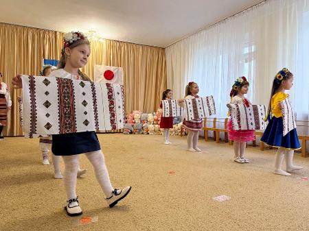３日、ウクライナ首都キーウ近郊のデミディフ村で、給食センターの完成を祝いダンスを披露する幼稚園児ら（共同）