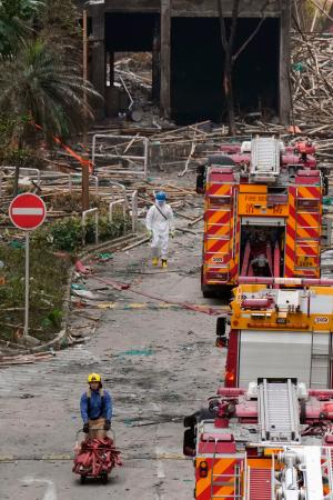 火災が起きた高層住宅群周辺で消火ホースを片付ける消防士＝４日、香港（共同）