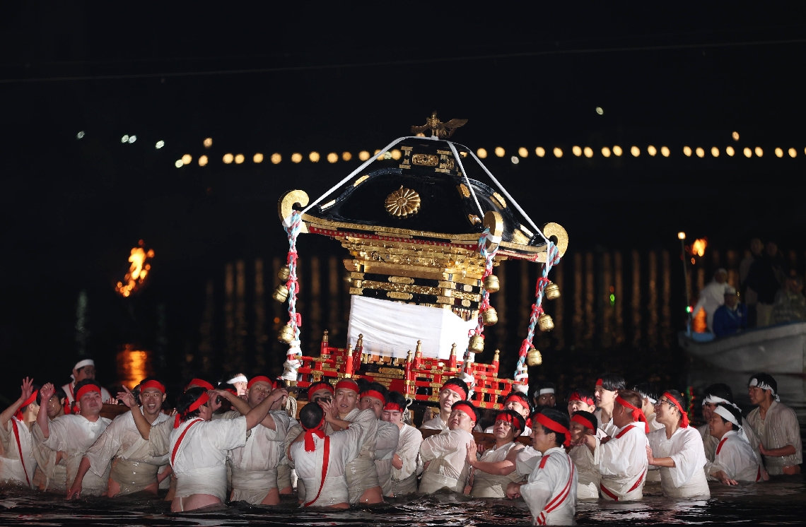 みこしを担いで豪快に川を渡る男衆＝５日夜、豊後高田市の桂川