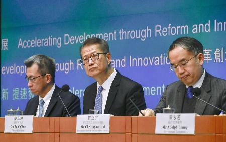 記者会見で財政予算案について説明する陳茂波財政官（中央）＝２月、香港