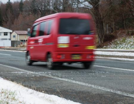 うっすらと雪が積もった岩手県内の山間部を走る郵便局の軽バン＝１１月