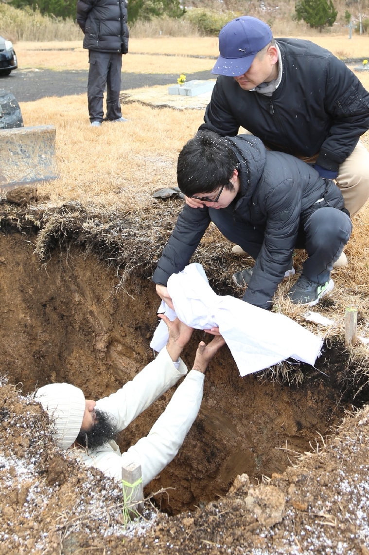 深く掘った土の中に埋葬するため、ディヤーちゃんの亡きがらを手渡す父親のユハン・クエクさん（左から２人目）