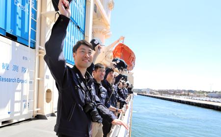 オーストラリア西岸のフリマントルを出港し、観測船「しらせ」の甲板で見送りに来た人たちに帽子を振る隊員ら＝８日（南極観測隊同行記者撮影）