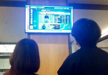 岩手県宮古市の海沿いにあるホテルのロビーで、津波警報を伝えるテレビ画面を見守る宿泊客＝９日未明