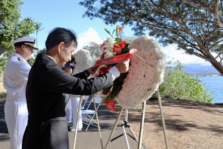 ８日、米ハワイ州フォード島で開かれた日米合同追悼式典で、献花する長徳英晶・駐ホノルル総領事（手前）と、コリンズ米ハワイ方面海軍司令官（共同）