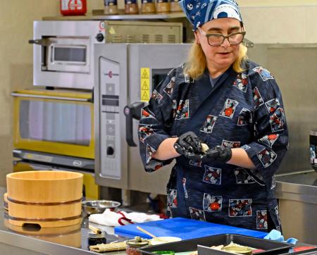 ８日、キーウにある国立貿易経済大で、すしの握り方を実演するラリサ・バルスカさん（共同）