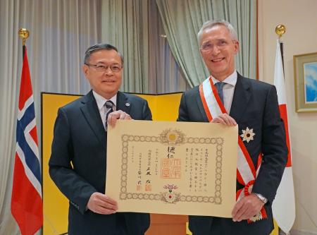 オスロの日本大使公邸で開かれた叙勲伝達式で、杉山明大使（左）から勲記を手渡されたノルウェーのストルテンベルグ財務相＝１２日（共同）