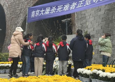 「南京大虐殺」の犠牲者を悼み、献花場で黙とうする子どもたち＝１３日、中国江蘇省南京（共同）