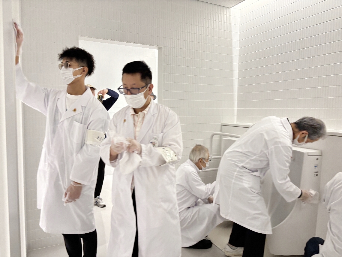 無言で怪しく入念に、雑巾がけをする大分圏清掃整理促進運動会メンバー＝大阪市の大阪中之島美術館