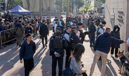 リンゴ日報の創業者、黎智英氏への判決公判が開かれる裁判所前を警戒する治安当局者ら＝１５日、香港（共同）