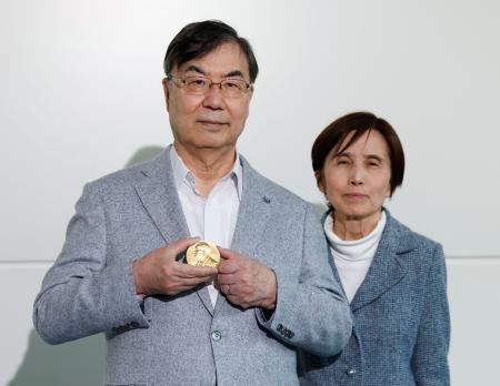 スウェーデンから帰国し、ノーベル生理学・医学賞のメダルを手にする坂口志文大阪大特任教授。右は妻教子さん＝１７日午後、羽田空港