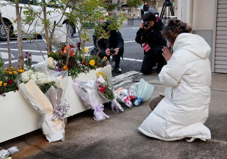 王将フードサービス本社前で手を合わせる遺族の大東真弓さん＝１９日朝、京都市山科区