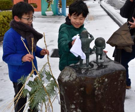 「水木しげるロード」にある妖怪などのブロンズ像にしめ飾りを取り付ける子どもたち＝２６日、鳥取県境港市