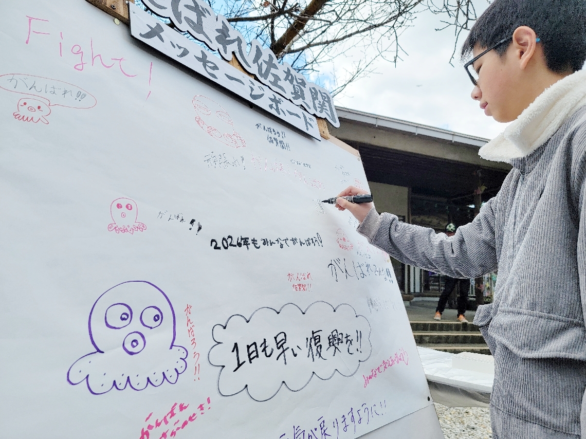 被災者を応援するメッセージをボードに書き込む参拝者