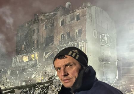 ２日、ロシア軍の空爆で破壊されたアパートと男性住民＝ウクライナ東部ハルキウ州（ロイター＝共同）