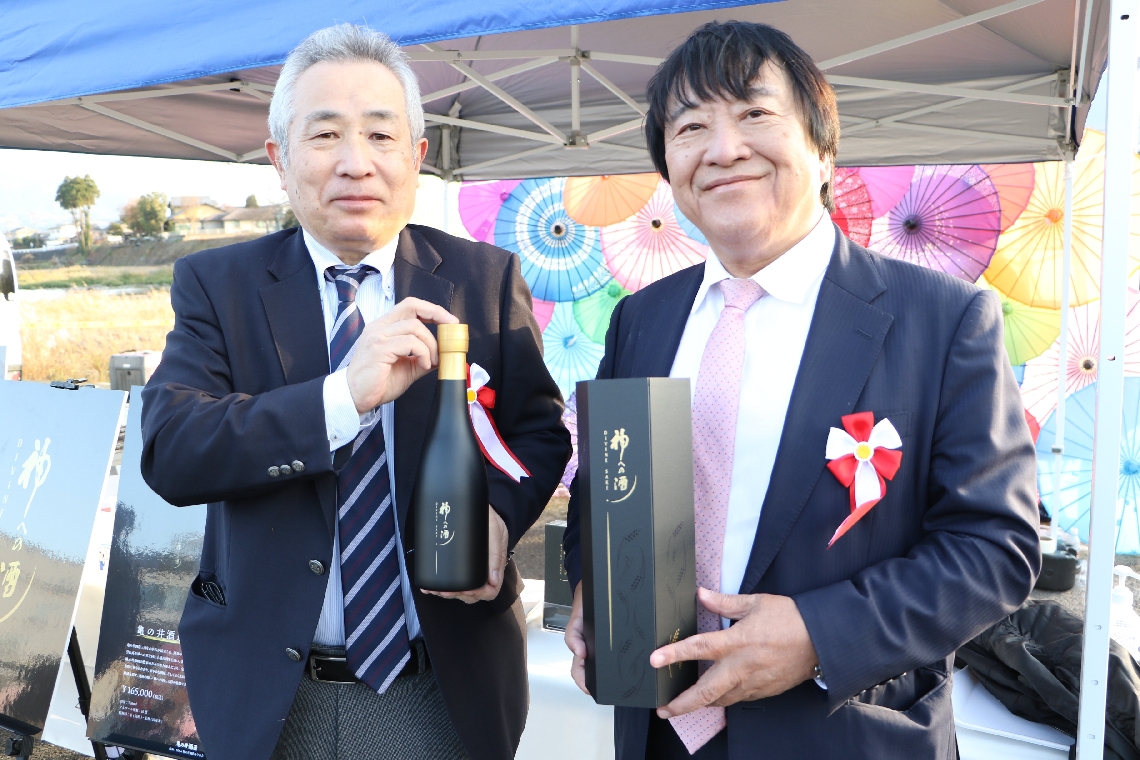 日本酒「神への酒」を造った亀の井酒造の長野雄人代表（左）とティーアンドエスグループの稲葉孝政会長＝玖珠町帆足の玖珠川河川敷