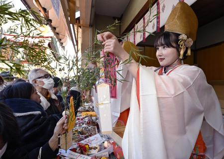 今宮戎神社で「十日えびす」の幕開けとなる「宵えびす」が始まり、参拝客の福ザサに縁起物を取り付ける福娘＝９日午前、大阪市浪速区