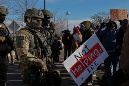 ９日、米ミネアポリスで、女性が死亡した現場付近を警備する移民・税関捜査局の職員ら（ロイター＝共同）