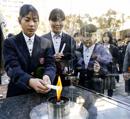 「１・１７希望の灯り」の分灯が始まり、ろうそくに火を移す中学生＝１０日午後、神戸市中央区の東遊園地