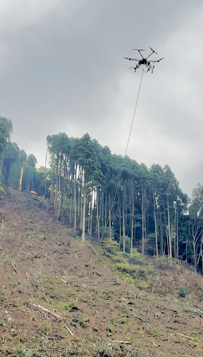 尾根の支柱からリードロープを運ぶドローン