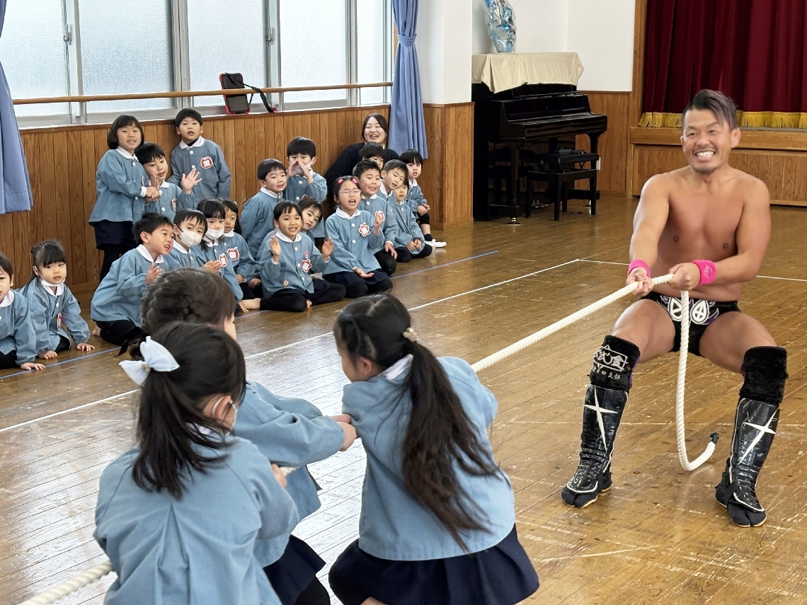 カトリック海星幼稚園の園児と綱引きをする佐々木日田丸選手＝２１日、大分市