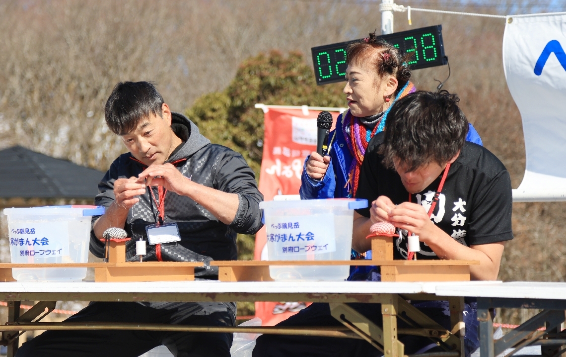 寒さにかじかむ手で針の穴に糸を通す参加者ら