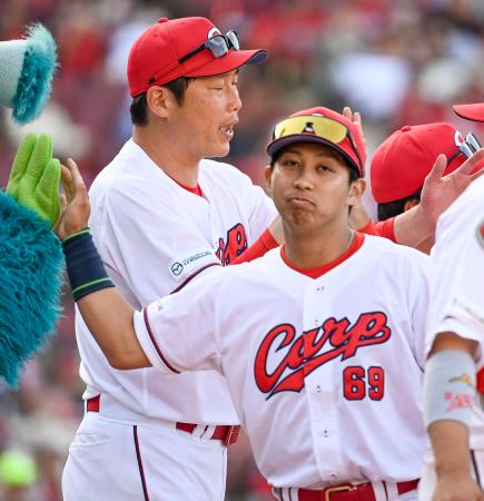 ２０２４年５月、巨人戦に勝利し広島の新井監督（左）とタッチを交わす羽月隆太郎内野手＝マツダ