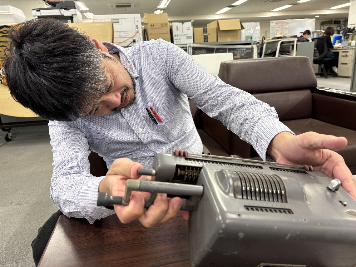 どうやって使うのか分からず、計算機を調べる大分合同新聞社の記者