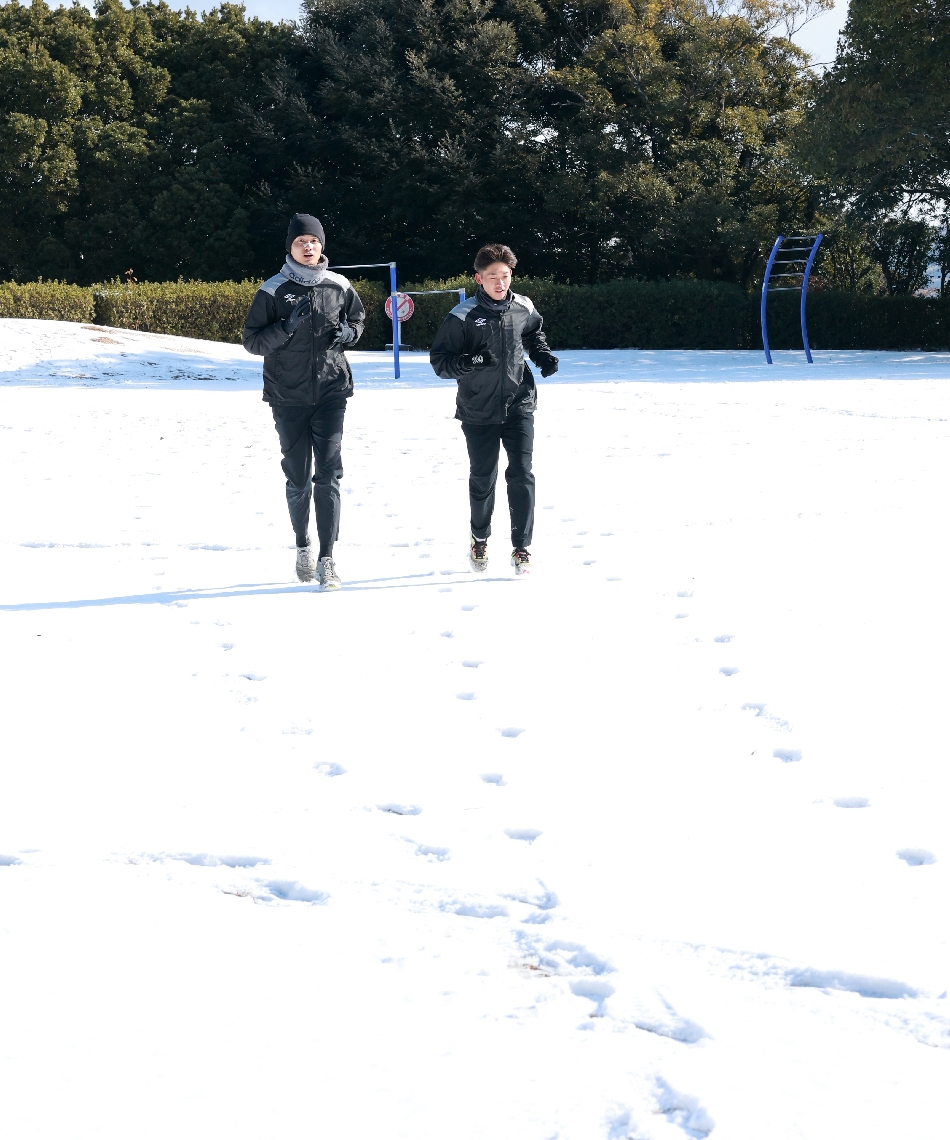 雪が積もる高尾山自然公園で走る人たち＝８日午前１０時２１分、大分市横尾