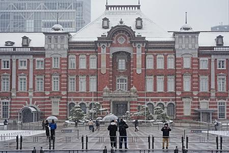 雪が降る中、ＪＲ東京駅前を訪れた人たち＝８日午前