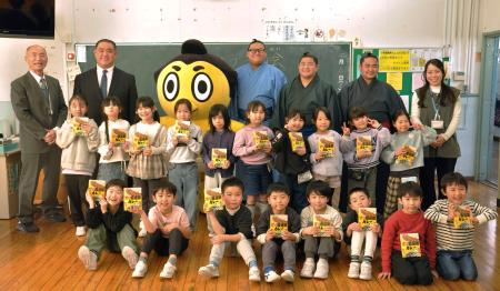 「甘口国技館カレー」を贈呈し、言問小学校の児童と記念写真に納まる日本相撲協会広報部の西岩親方（後列左から２人目）ら＝１２日、東京都墨田区