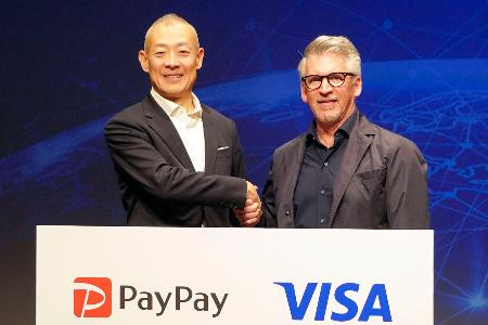 記者会見で米ビザの幹部と握手するペイペイの中山一郎社長（左）＝１２日午後、東京都内