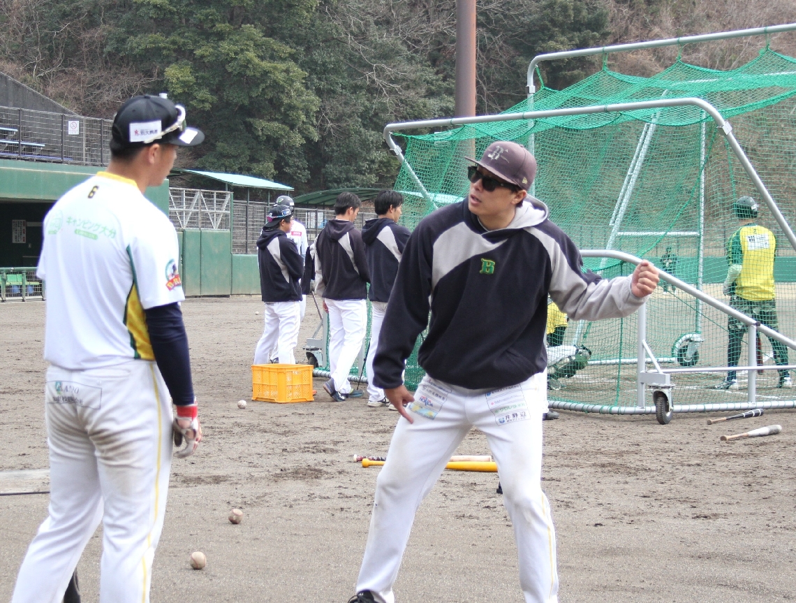 選手にバッティングの指導をする水本大志監督兼選手（右）＝フジジンの杜スタジアム