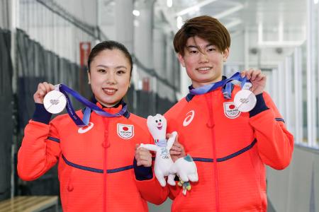フィギュアスケート団体で獲得した銀メダルを掲げる、アイスダンスの吉田唄菜（左）と森田真沙也＝京都府宇治市