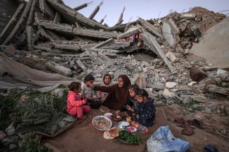 １８日、ガザ北部ガザ市で、ラマダン（断食月）中の日没後に許される食事を取るパレスチナ人（ゲッティ＝共同）