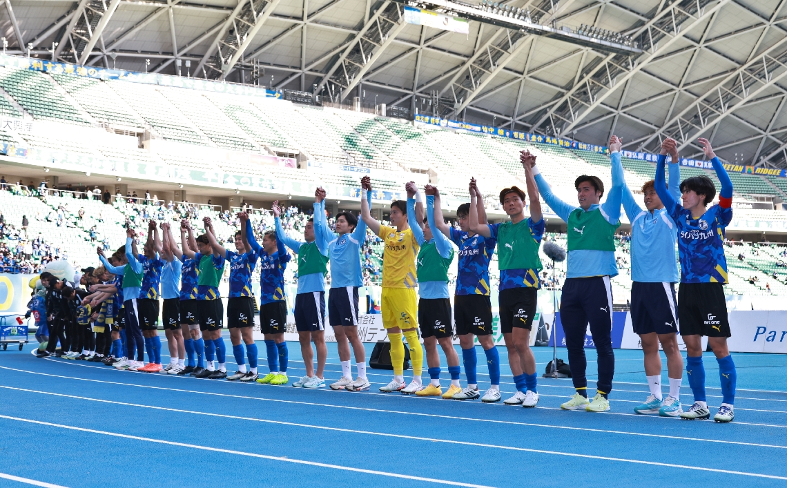 スタンドのサポーターたちと勝利を喜ぶ大分の選手たち
