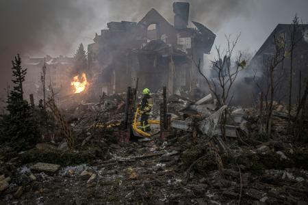 ２２日、ロシアがミサイルや無人機で攻撃したウクライナ首都キーウ郊外の現場で活動する消防隊員。２４日で侵攻から４年となる（ゲッティ＝共同）