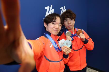 イタリア・ミラノのマルペンサ空港で、出発前に撮影に応じるフィギュアスケート男子の鍵山優真（左）と佐藤駿＝２３日（代表撮影・共同）