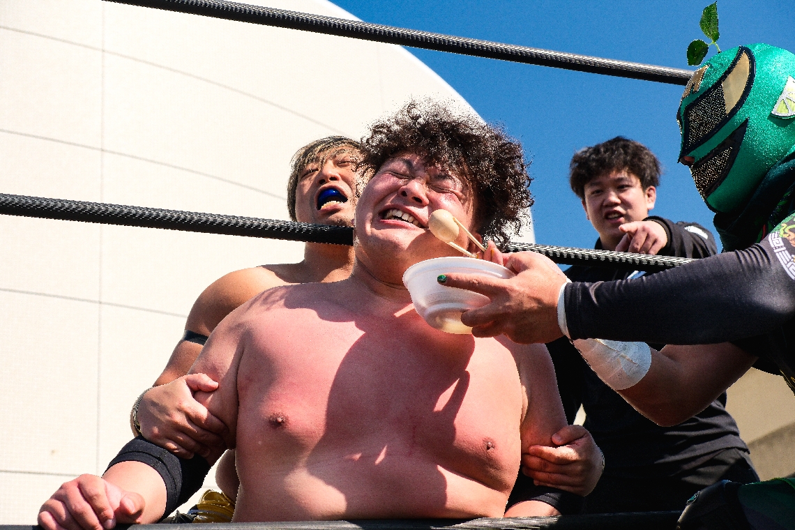 熱々のおでんのタマゴで反則攻撃するスーパー・カボストロング魔神（右）